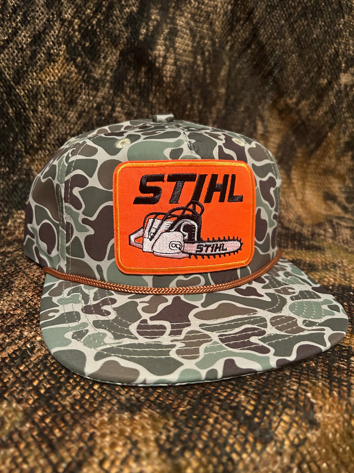 STIHL chainsaw patch on a jungle Camo ropebrim SnapBack hat