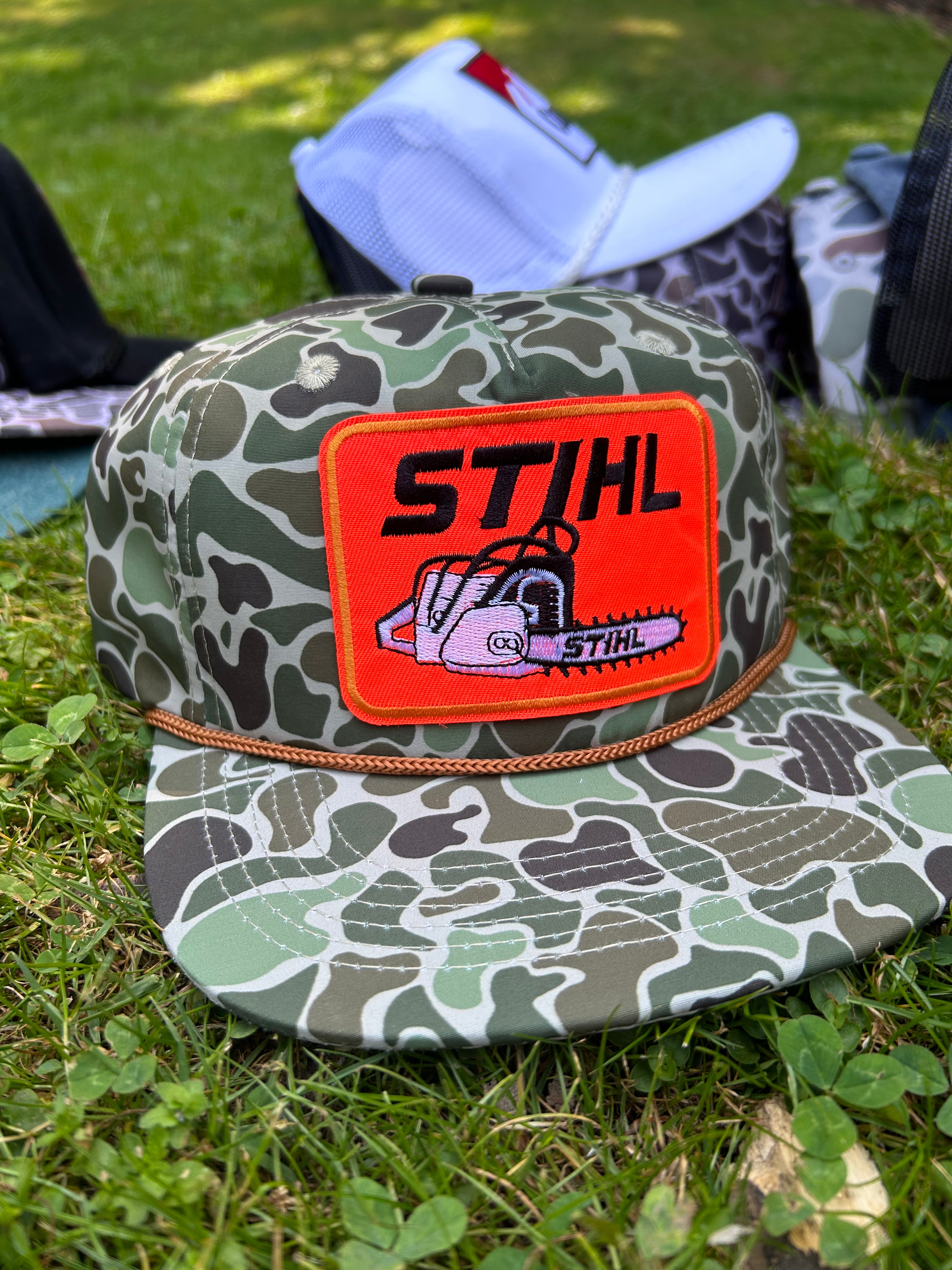 STIHL chainsaw patch on a jungle Camo ropebrim SnapBack hat