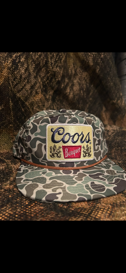 Coors gold patch on a green camo SnapBack hat