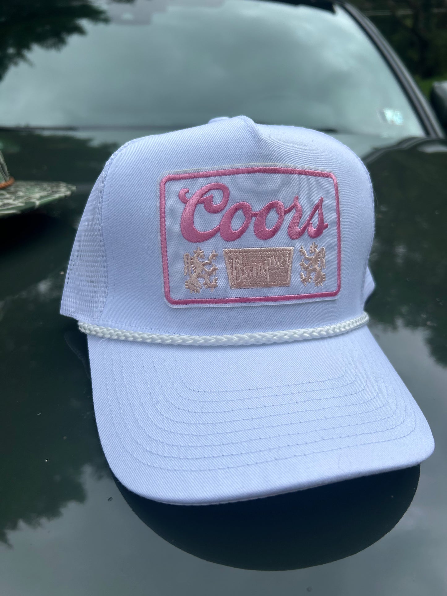 Coors Banquet pink patch on a white trucker hat