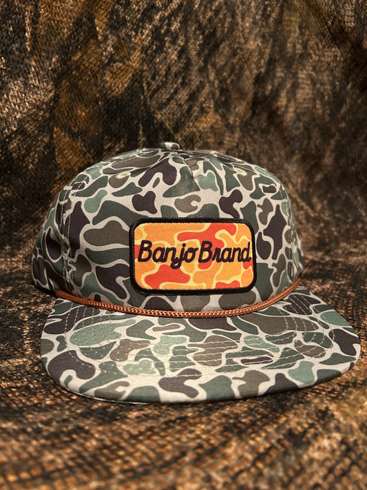 Banjo Brand script patch on a jungle Camo rope brim SnapBack hat
